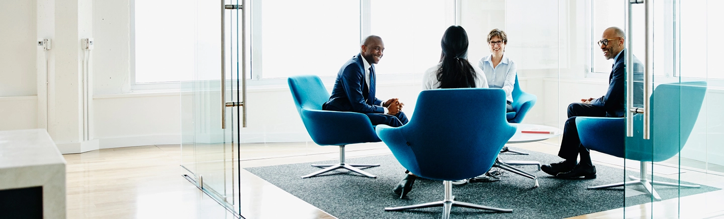 4 senior diverse business leaders sitting around casual roundtable