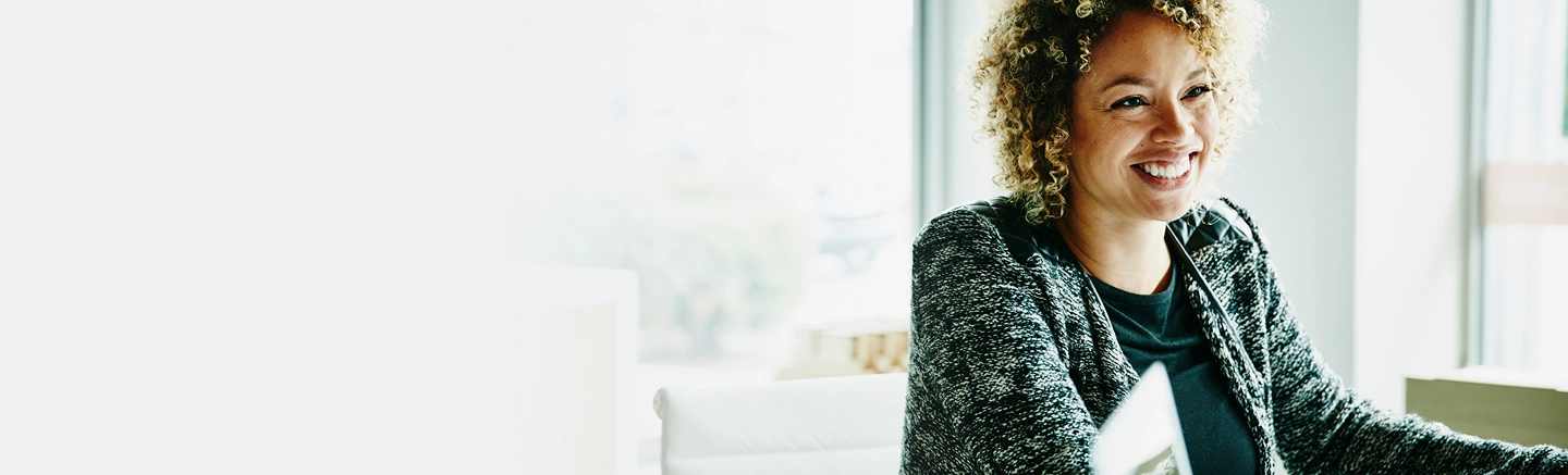 Black woman with curly hair smiling at colleague