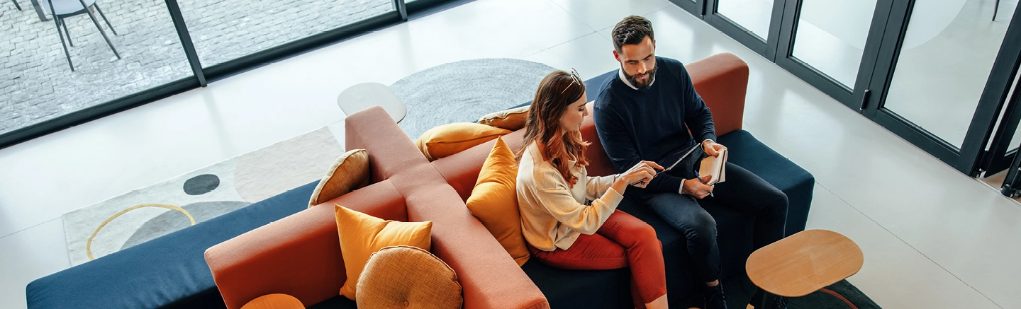 Man and woman looking at work sitting in a lounge couch