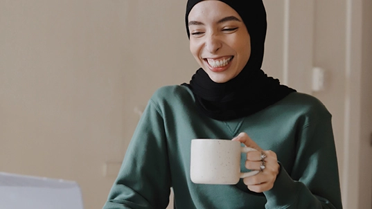 Woman drinking coffee in front of a computer.