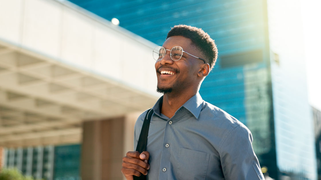 A man with a smile on his face walks around a city.