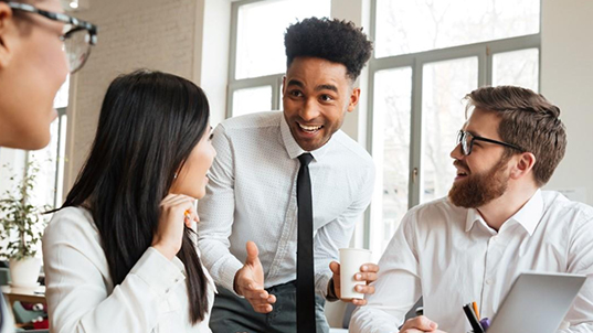 Three people talk amongst themselves excitedly on an office.