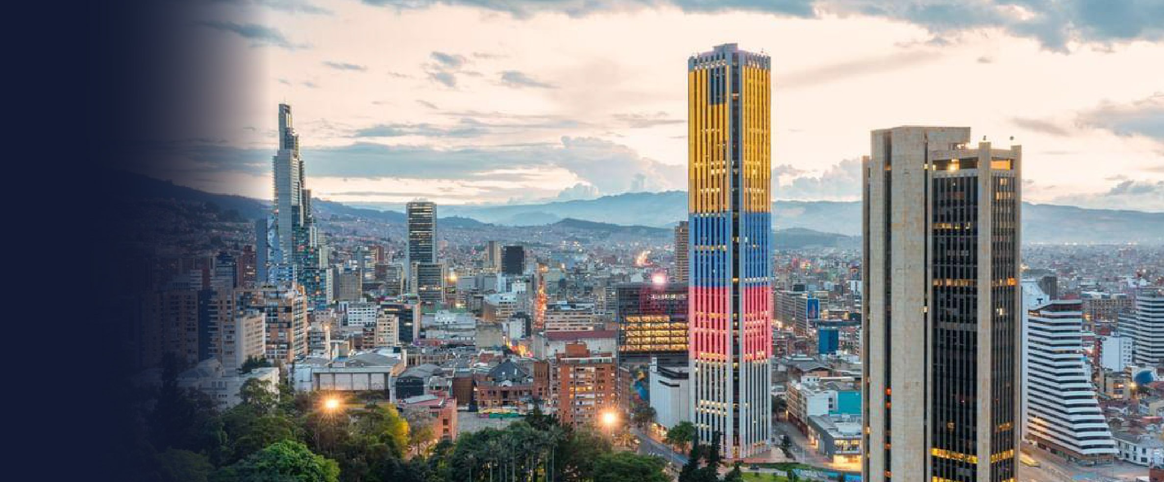 A picture of the Colombian city with several buildings. One of them is light up with the Colombian flag colors: Yellow, blue and red.