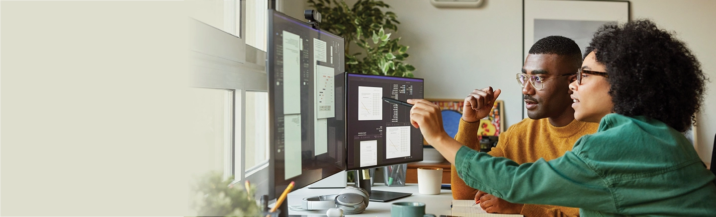 Man and woman staring at something on desktop screen.