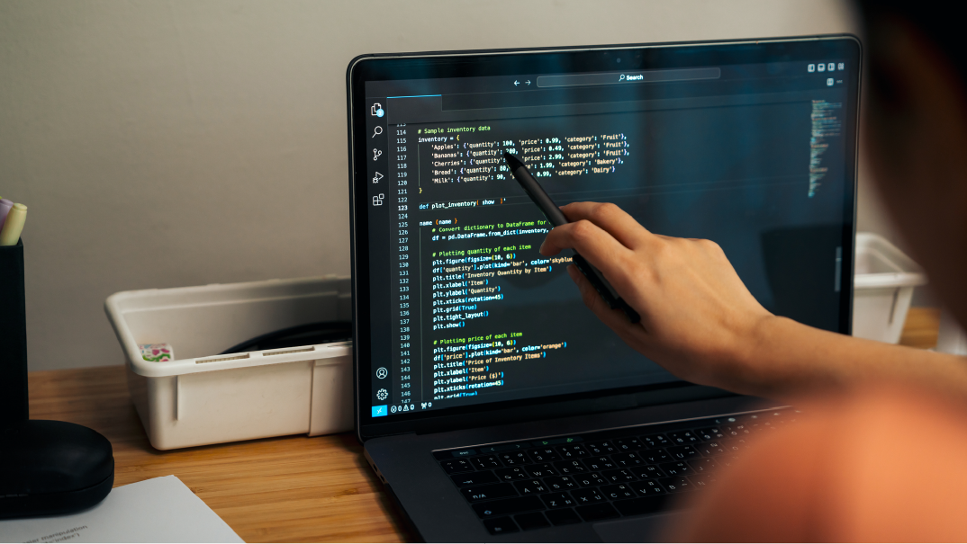A hand uses a black pen to point on HTML code on a laptop. Discover resume tips for Java Developers.
