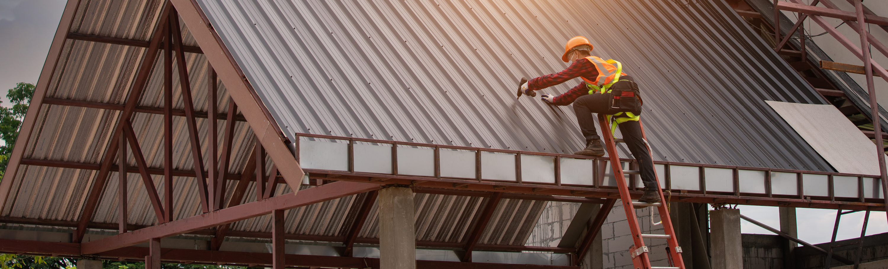 Worker with a drill on a roof in construction clothing