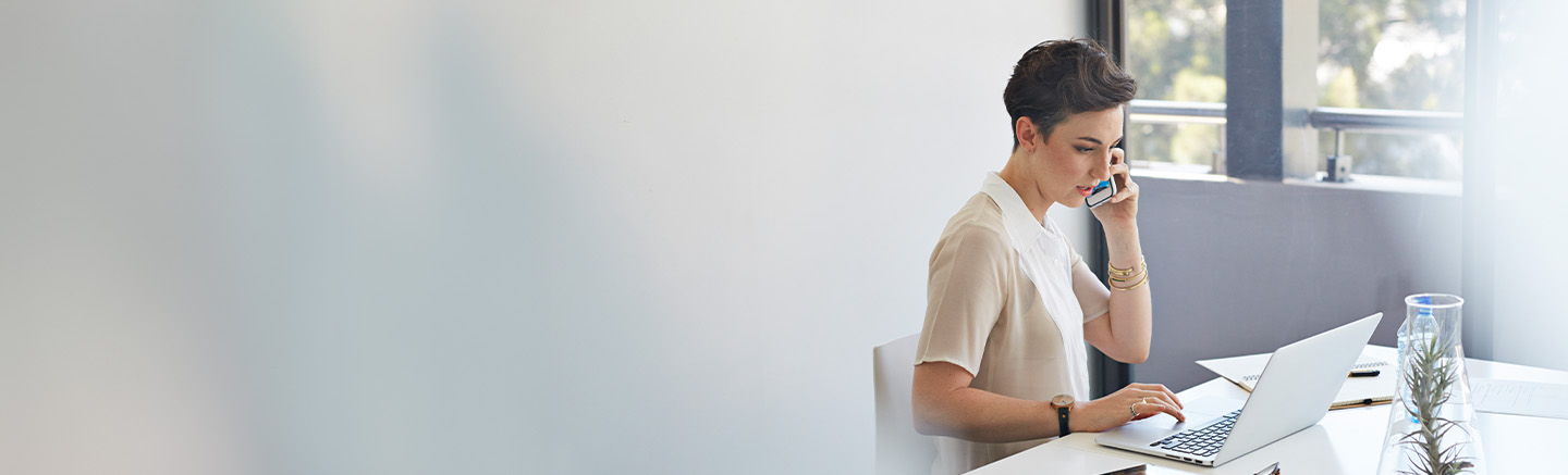 Woman with short hair on cellphone at her laptop